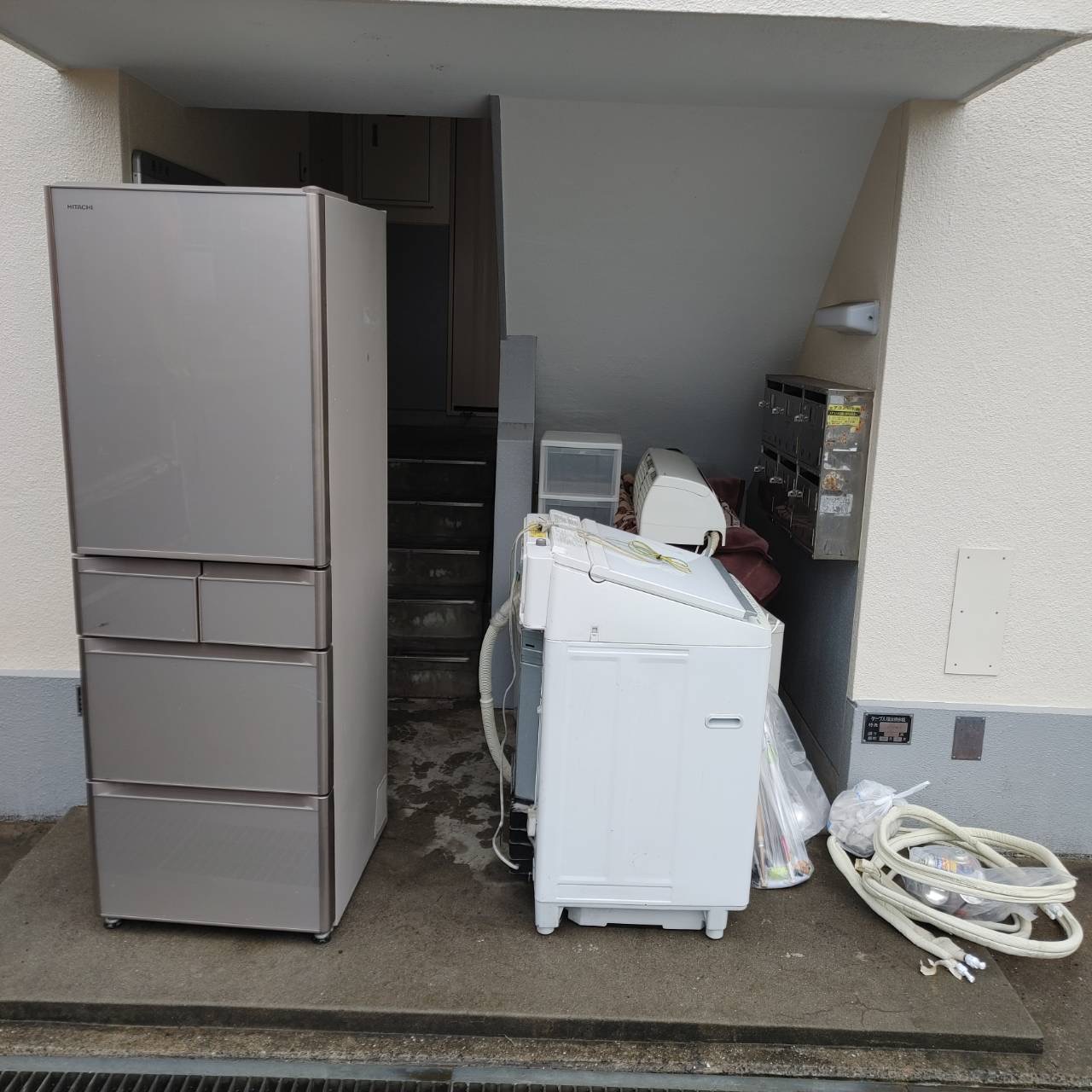 鹿児島市紫原での不用品回収作業。アパートの入り口付近に搬出された冷蔵庫、洗濯機、エアコンなどの大型家電。