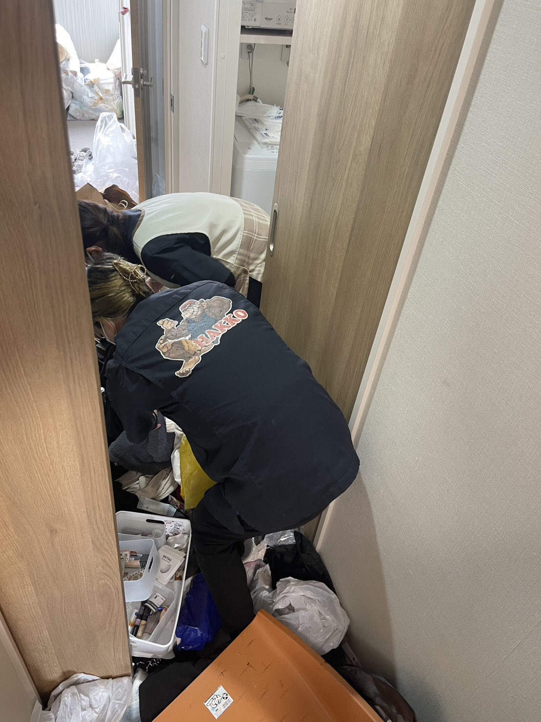 鹿児島市のごみ屋敷片付け現場にて、室内に散乱した不用品や生活ゴミを丁寧に分別・回収する株式会社HAKKOの女性スタッフの作業風景