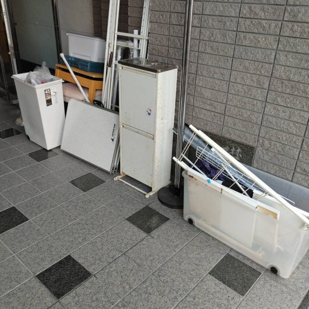 マンション共用部に集積された不用品（家電・収納用品・天板など）