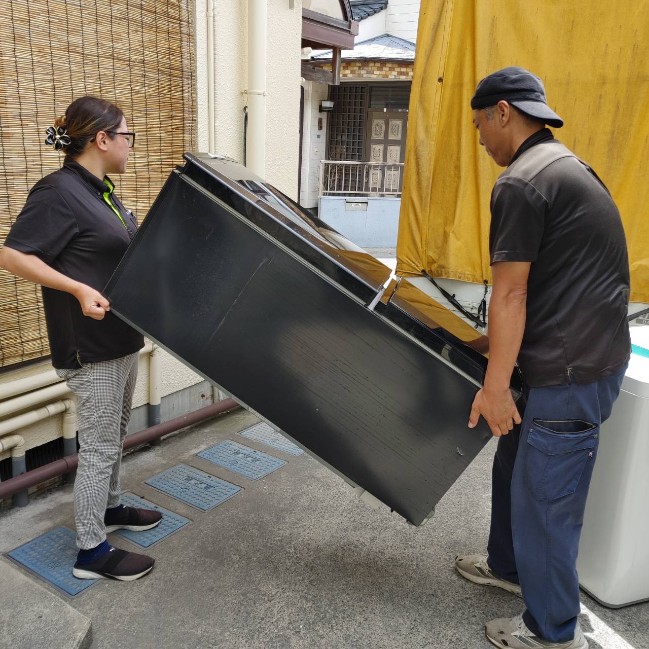 鹿児島市 食器棚処分 スタッフ2名が冷蔵庫をトラックへ搬出している様子