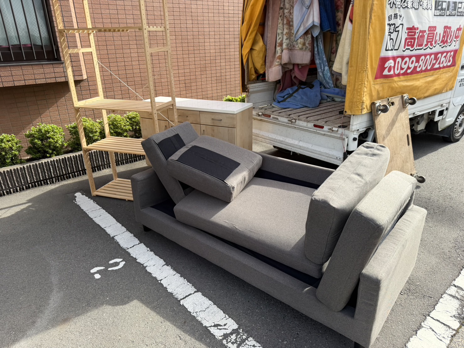 作業前(駐車場の区画に、カウチ付きソファ、木製棚、カウンター収納が並んでいる)